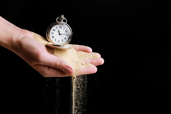 Zseb-órát kezében ezüst és homok folyik el a fekete háttér — Stock Fotó