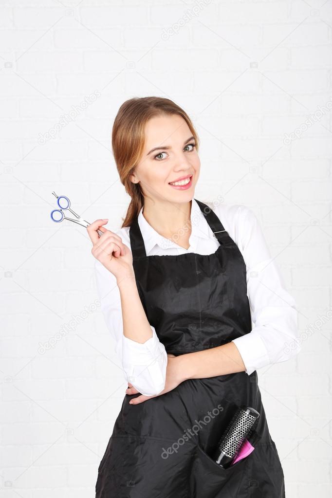 Beautiful girl hairdresser on light background