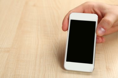 Akıllı cep telefonu ahşap masa arka planda tutan el
