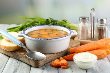 Havuç Çorbası, malzemeler ve ışık arka plan üzerinde renkli ahşap masa üzerinde otlar ile kompozisyon