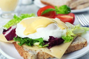 Yumurta Benedict ile tost ve ahşap masa üzerinde tabakta domates