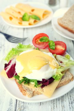 Yumurta Benedict ile tost ve ahşap masa üzerinde tabakta domates