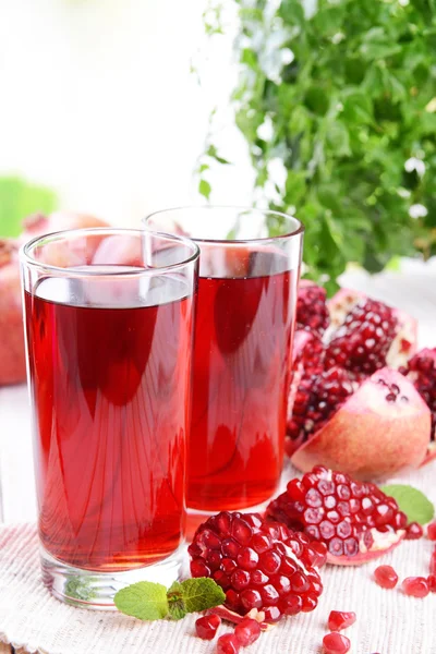 Ripe pomegranates with juice on table on light background — Stock Photo, Image