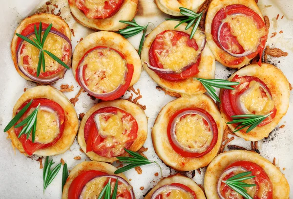 Pequeñas pizzas sobre papel de hornear de cerca — Foto de Stock