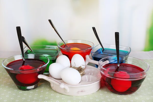 Яйца жидкого цвета из стекла на столе на ярком фоне — стоковое фото