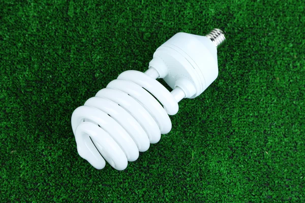 Energiesparlampe auf grünem Gras Hintergrund — Stockfoto