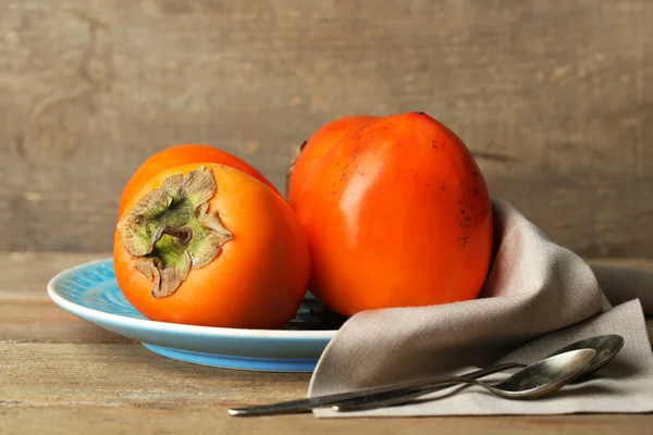 Ripe sweet persimmons, on wooden table — Stock Photo, Image