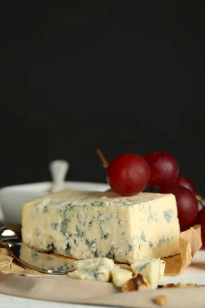 Stilleven met smakelijke blauwe kaas op tafel, op donkere achtergrond — Stockfoto