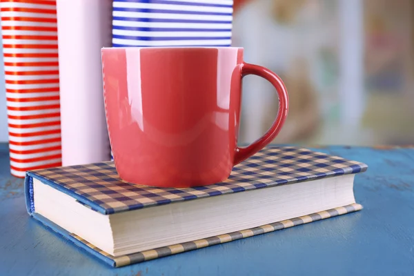 Χρώμα φλιτζάνι τσάι με βιβλία στο τραπέζι, στο φως θολή φόντο — Φωτογραφία Αρχείου