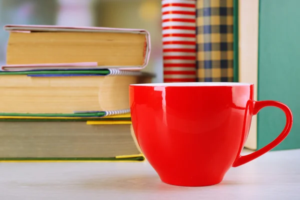 Färg kopp te med böcker på bord, på ljus suddig bakgrund — Stockfoto