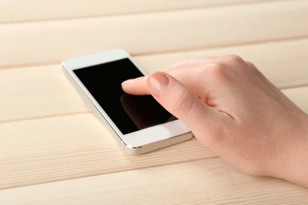 Mano usando teléfono móvil inteligente sobre fondo de mesa de madera — Foto de Stock