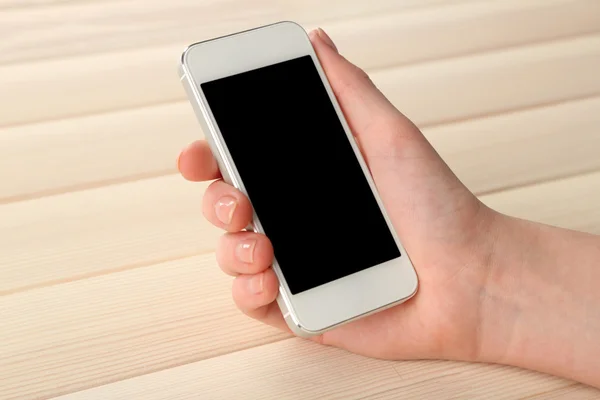 Mano usando teléfono móvil inteligente sobre fondo de mesa de madera — Foto de Stock