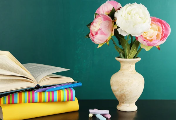 Composición sobre escritorio con libros y flores sobre fondo de pizarra verde —  Fotos de Stock