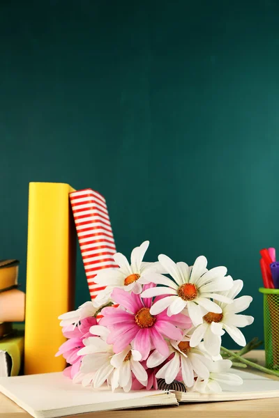 Komposition på skrivebord med bøger og blomster på grøn tavle baggrund - Stock-foto