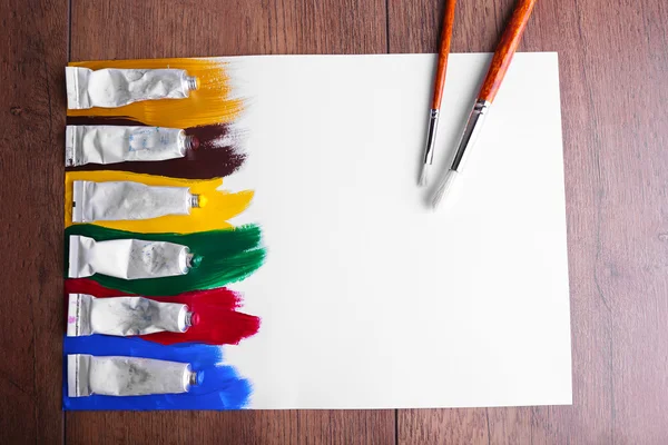 Colpi di vernice colorata su foglio di carta e sfondo tavolo in legno — Foto Stock