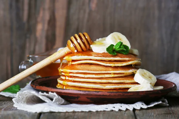 Tumpukan pancake dengan mint, madu dan irisan pisang di latar belakang kayu pedesaan — Stok Foto