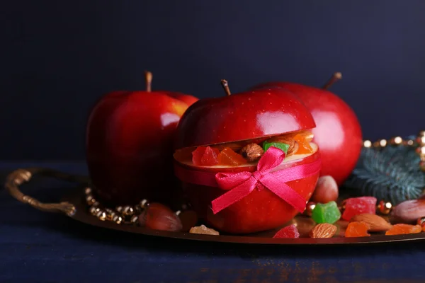 Red apples stuffed with dried fruits on metal tray on color wooden table and dark background — Stock Photo, Image