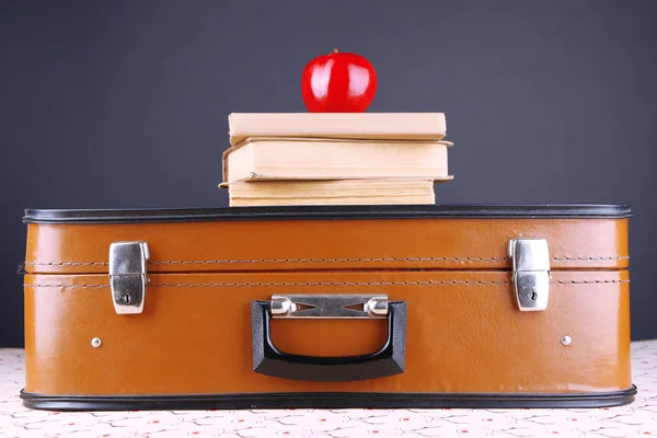 Vintage-Koffer mit Bücherstapel auf gemusterter Oberfläche und dunklem Hintergrund — Stockfoto