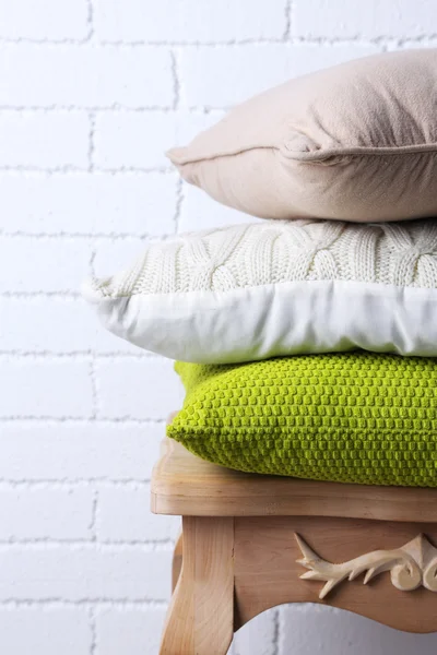 Kussens op kleine houten tafel en witte bakstenen muur achtergrond — Stockfoto