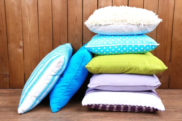 Hill of colorful pillows on rustic wooden background — Stock Photo, Image