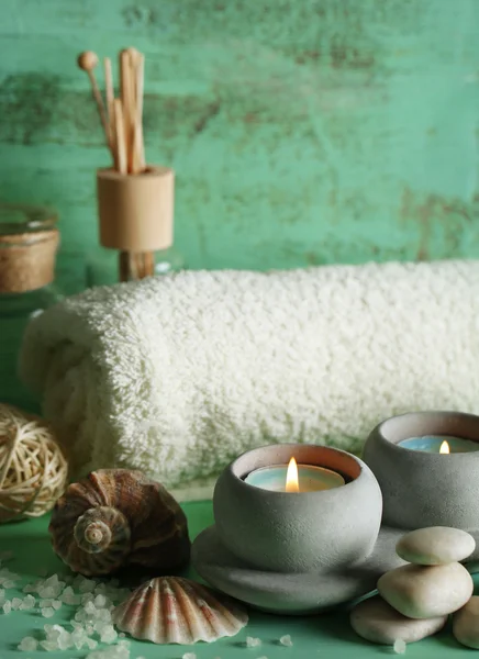 Kaarsen, handdoek, zeezout en spa stenen op houten ondergrond — Stockfoto