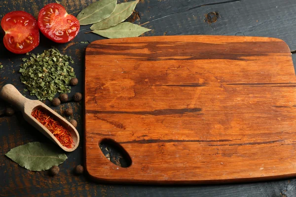 Diferentes especias y hierbas con tabla de cortar sobre fondo de mesa de madera de color — Foto de Stock