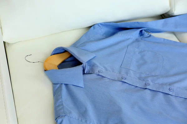 Camisa azul en percha, sobre fondo de sillón blanco — Foto de Stock