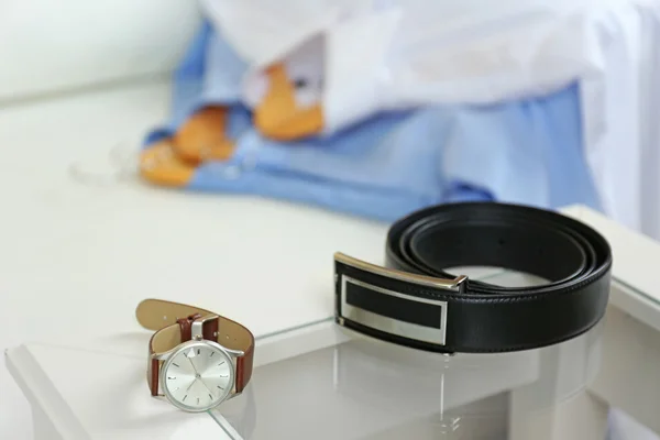 Men's shirts on armchair near belt and watch on coffee table, closeup — Stock Photo, Image