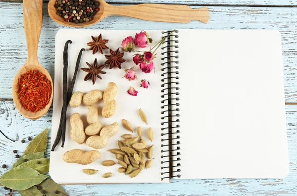 Especiarias com livro de receitas sobre fundo de mesa de madeira cor — Fotografia de Stock