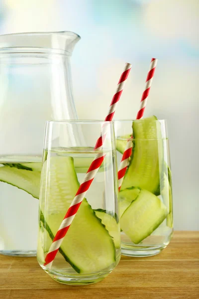 Water with cucumber on wooden table and bright background — Stock Photo, Image