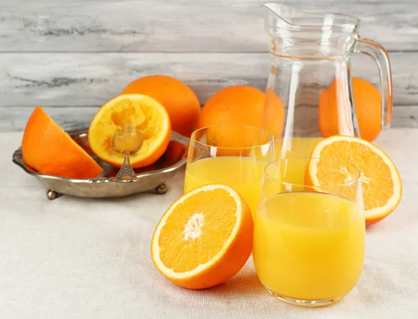 Склянка апельсинового соку зі скибочками на металевому лотку на столі та кольоровим дерев'яним фоном стін — стокове фото