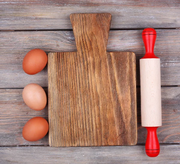 Tagliere con uova su tavole di legno rustico sfondo — Foto Stock