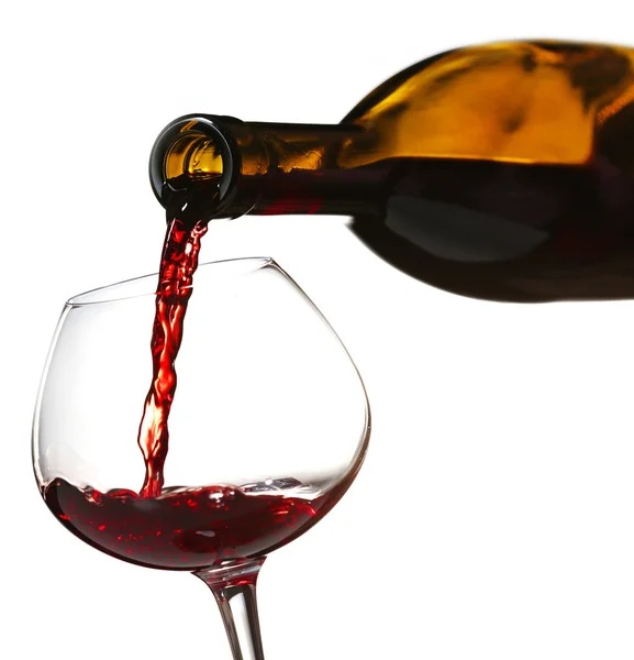 Pouring red wine from bottle into glass on color background — Stock Photo, Image