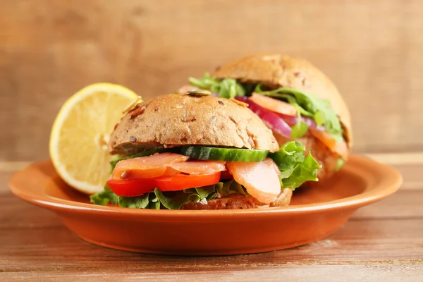 Sandwiches con salmón en plato, sobre fondo de madera — Foto de Stock