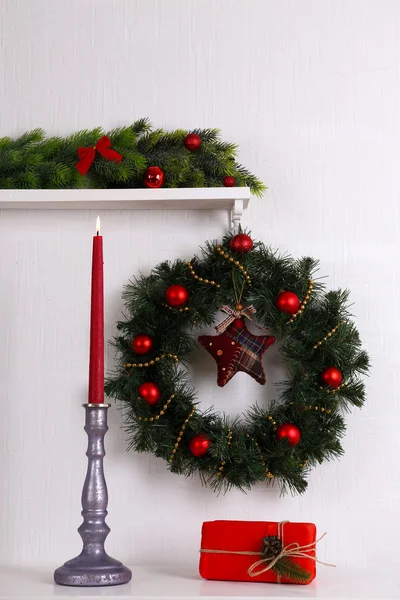 Kerstdecoratie met krans op plank op witte muur achtergrond — Stockfoto
