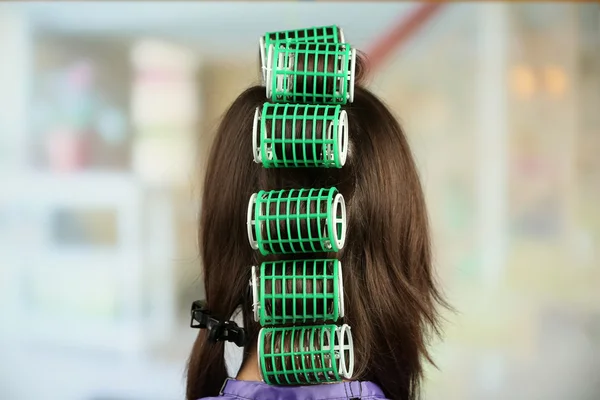 Long female hair during hair dressing with curler, close-up, on light background