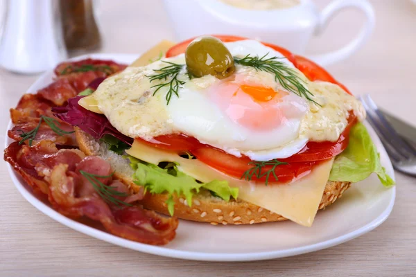 Sandwich with poached egg, tomato and bacon on plate on wooden background — Stock Photo, Image