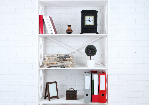 Bookshelves with books and decorative objects on brick wall background