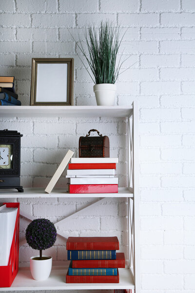 Bookshelves with books and decorative objects on brick wall background