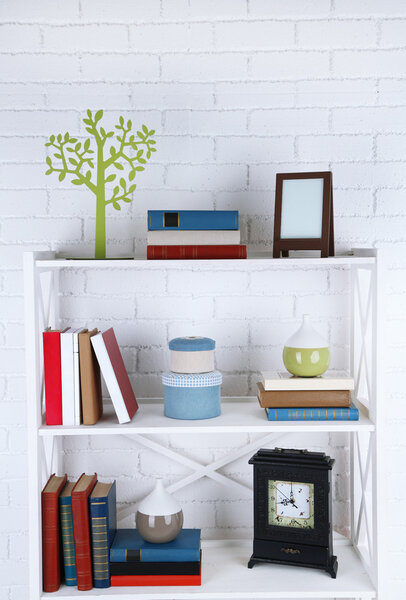 Bookshelves with books and decorative objects on brick wall background
