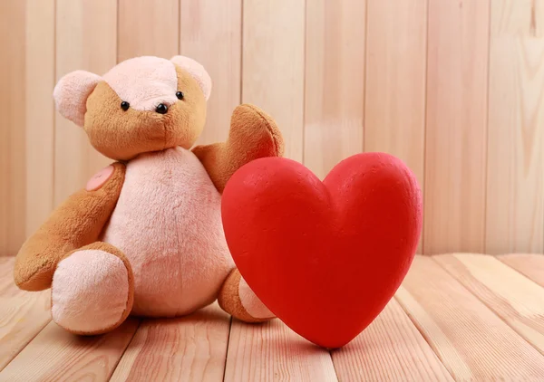 Oso de peluche con corazón rojo sobre fondo de madera —  Fotos de Stock