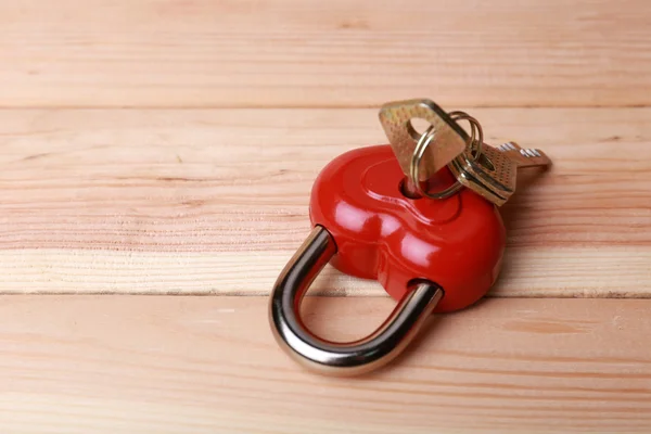 Candado en forma de corazón con llave sobre fondo de madera — Foto de Stock