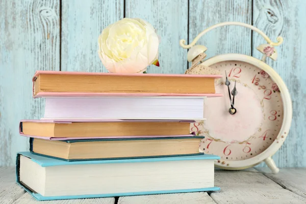 Libros con reloj sobre fondo de madera —  Fotos de Stock