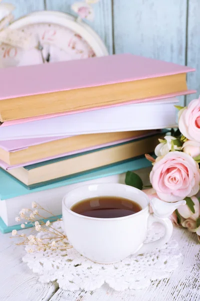 Kopje thee met boeken en bloemen op houten achtergrond — Stockfoto