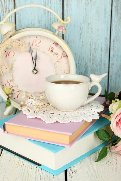 Чашка чая с книгами и цветами на деревянном фоне — стоковое фото