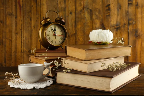 Kopje thee met boeken en klok op houten achtergrond — Stockfoto