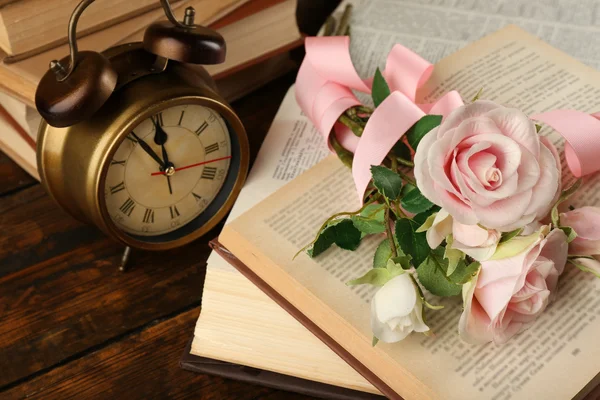 Libros con flores y reloj sobre fondo de madera —  Fotos de Stock