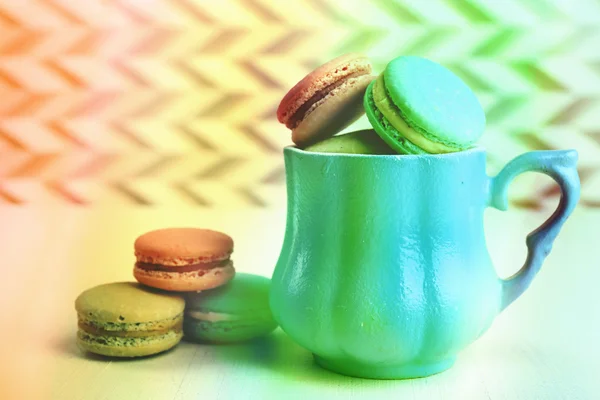 Sortimento de macaroons coloridos suaves na caneca na cor e fundo texturizado — Fotografia de Stock