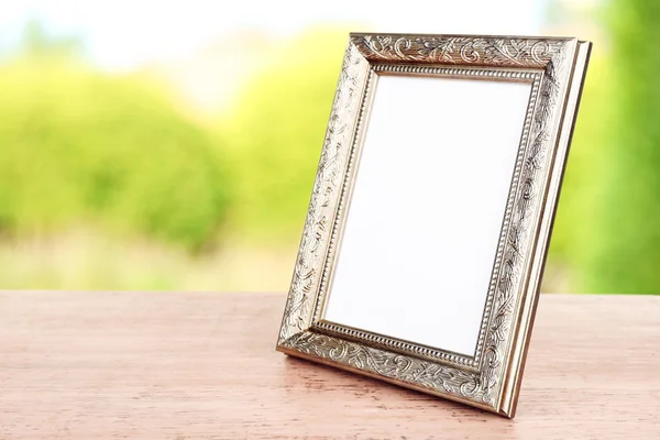 Photo frame on wooden table on nature background — Stock Photo, Image