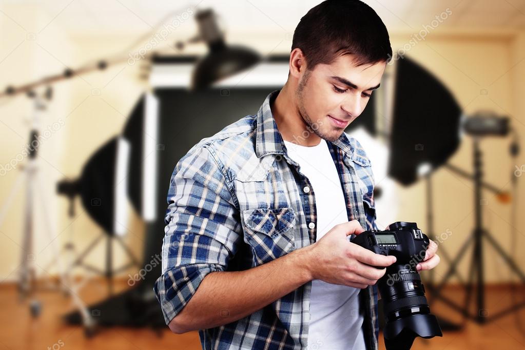 Handsome photographer with camera in photo studio